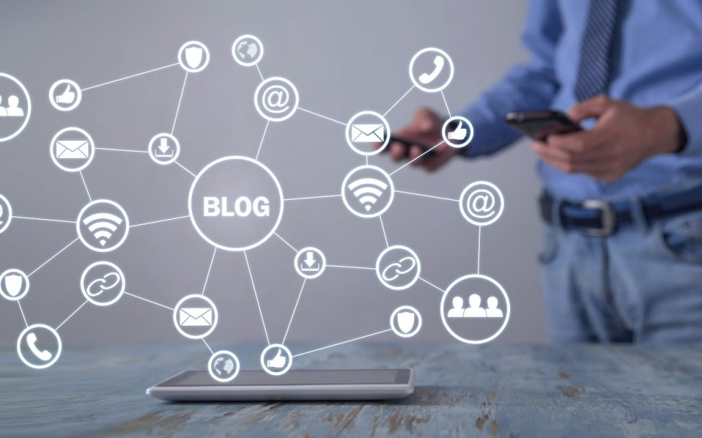 Blog strategy - stop writing for google and write for the person who's about to hire you. A person using a smartphone stands behind a tablet displaying digital icons connected by lines around the word "BLOG," representing online networking and communication.